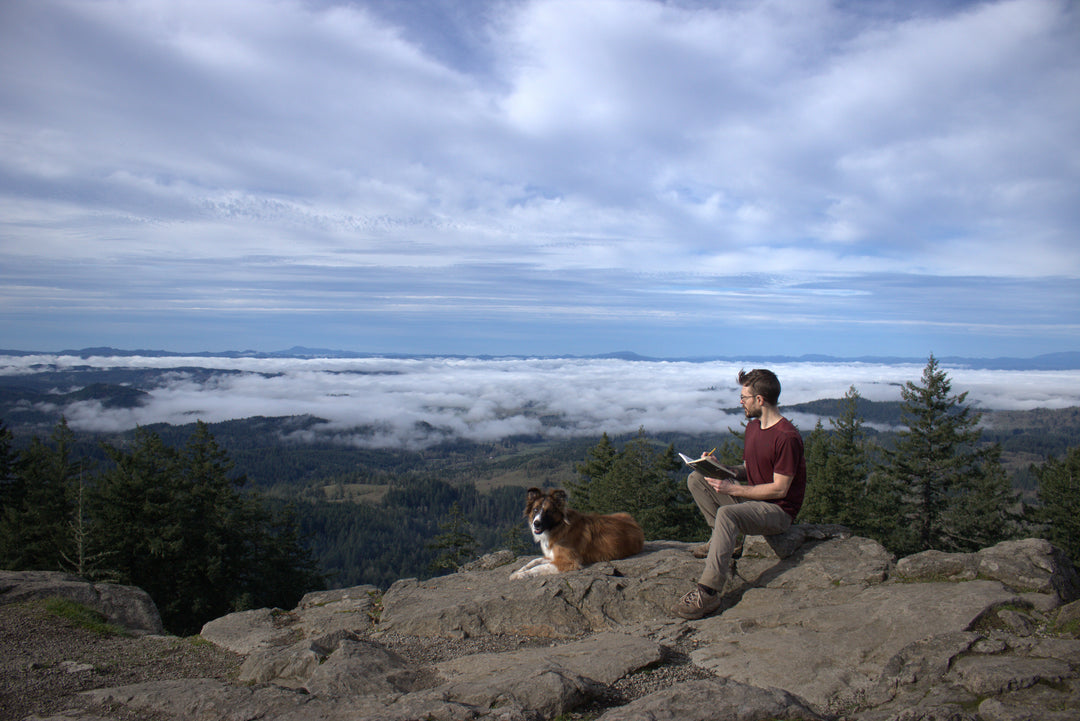 Brendan McCullough drawing on a mountain with his dog Cliff